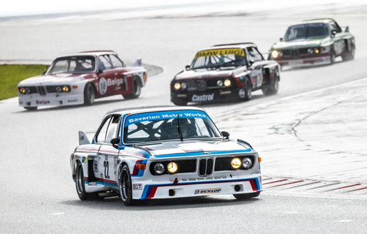 Classic BMW race cars mastering track driving techniques.